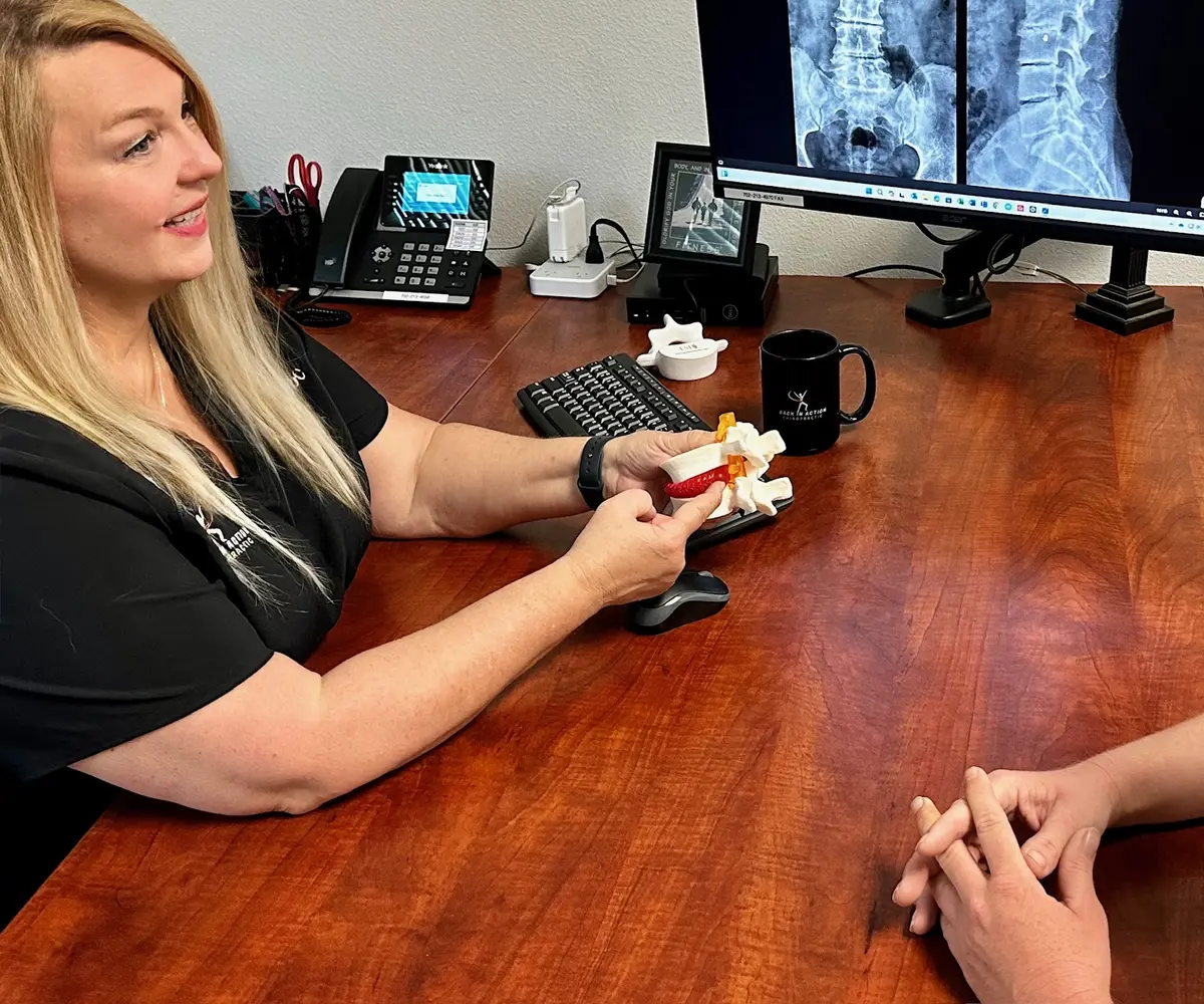 Dr. Michelle Binkowski using a spine model to explain sciatica alongside lumbar X-ray imaging in Las Vegas