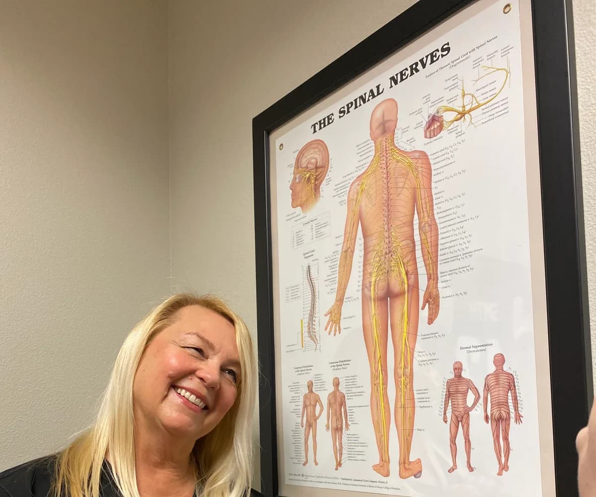 Dr. Michelle Binkowski beside a spinal nerve chart used to explain TMJ and jaw pain in Las Vegas