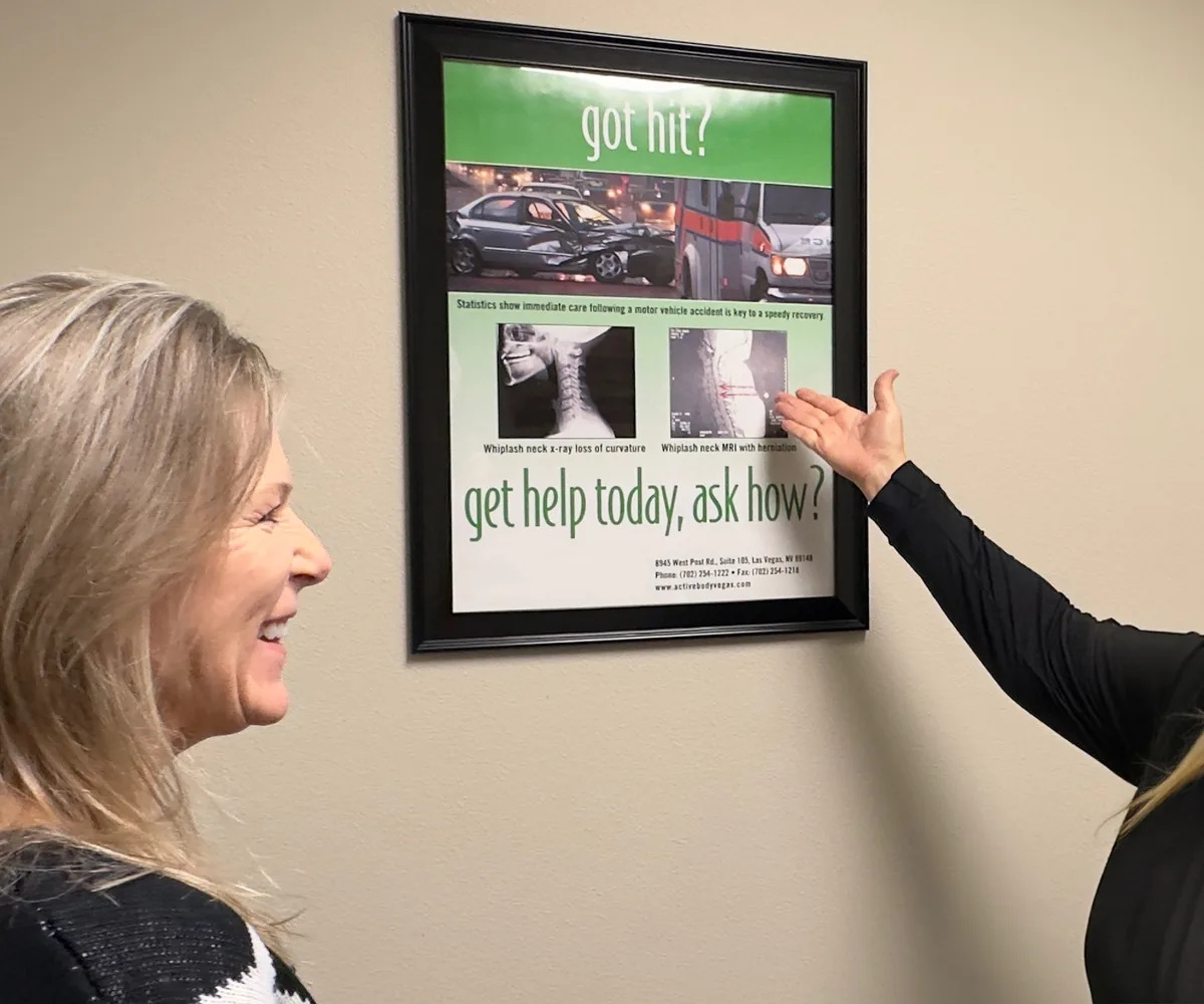 Dr. Michelle Binkowski beside an auto accident injury information poster at Back in Action Chiropractic in Las Vegas